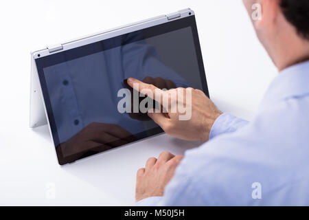 Close-up Of Man Touching Hybrid Laptop Screen With Finger On The White Desk Stock Photo