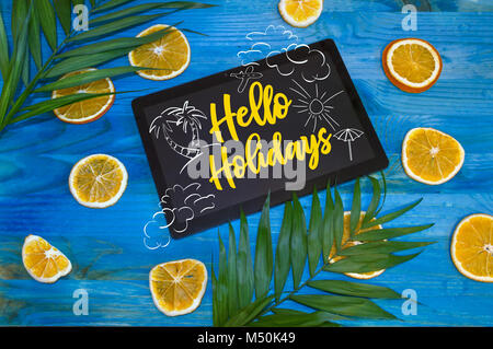 hello holidays concept with citrus fruits and palm leaves on blue wooden background Stock Photo