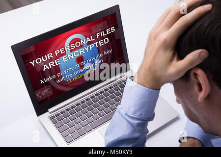 Worried Businessman Looking At Laptop With Ramsomware Word On The Screen At The Workplace Stock Photo