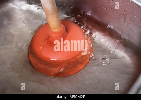 An Orange Cup Plunger In The Washbasin Filled With Water Stock Photo