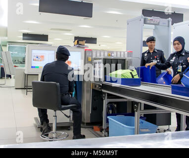 MALAYSIA, PENANG, NOV 14 2017, Checking luggage at the airport. A policeman watches a monitor baggage scanner. Stock Photo