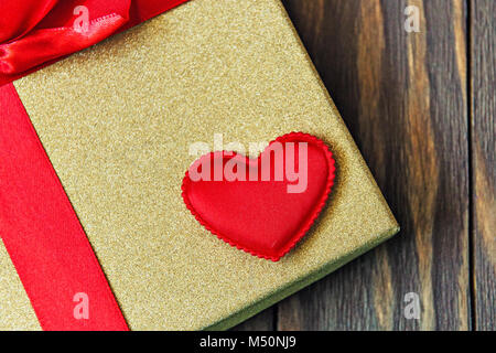 gift box with red bow and heart on wooden background. gift with love. Stock Photo