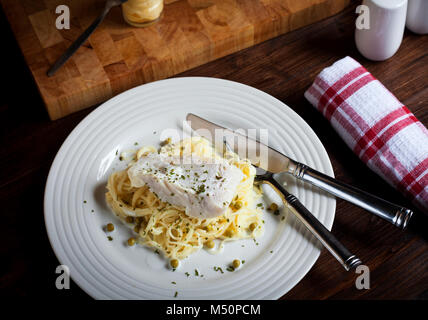 A healthy plate of white fish, peas and pasta on white plate Stock Photo