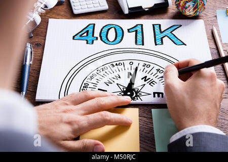 Man Writing 401k Pension Plan In Notepad On Desk Stock Photo