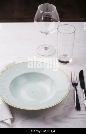 Empty plate, fork, knife and wine glasses on white table Stock Photo