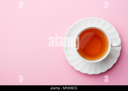 Tea in white cup on pink background. Copy space. Top view. Stock Photo