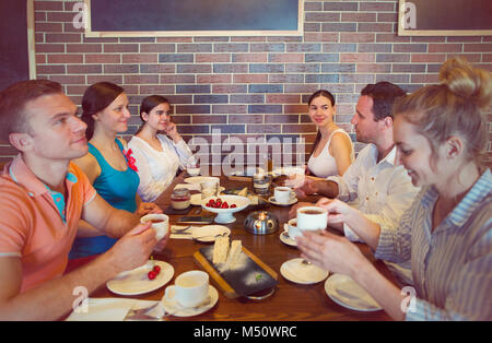Six cheerful friends chatting while lunch in restaurant. Friendship and food concept Stock Photo