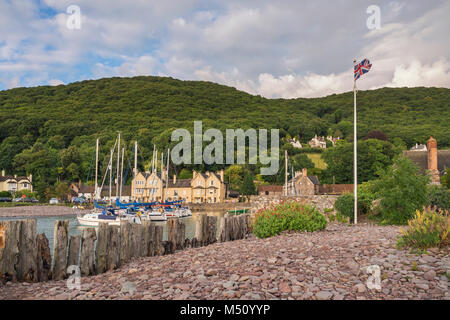 Summer morning in Porlock Weir, Somerset, England looking from the pebble beach towards the buildings around the harbour with visiting yachts moored u Stock Photo