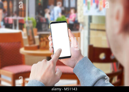 Man use mobile phone with isolated screen for mockup in coffee shop. Modern smart phone with round edges. Stock Photo