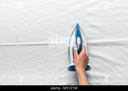 man ironing bed sheets Stock Photo