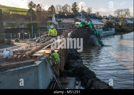 Workmen and a Caterpillar 320D excavator work on Skibbereen's flood defences, County Cork, Ireland. Stock Photo