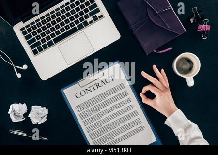 cropped shot of businesswoman showing okay sign at workplace isolated on black Stock Photo