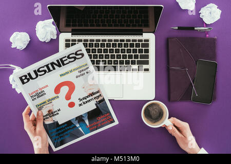 Cropped shot of businesswoman reading magazine at workplace on purple surface Stock Photo