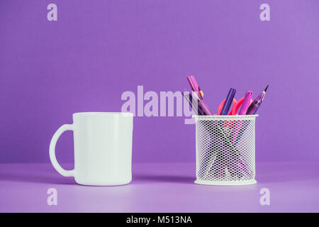 cup and pen holder on purple surface Stock Photo