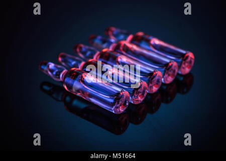 row of transparent glass ampoules with liquid on table Stock Photo