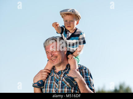 Grandfather carries grandson toddler boy on his shoulders Stock Photo