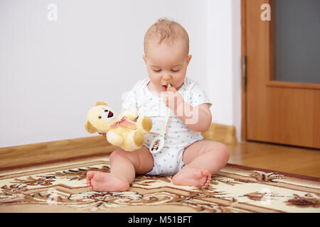 Adorable baby boy playing with plush toy in badroom in sunny day. Stock Photo