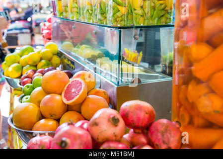 Close up street selling vendor of freshly sqeezed juices, smoothies and fruit salads on market place in Tel Aviv, Israel. Selective focus Stock Photo