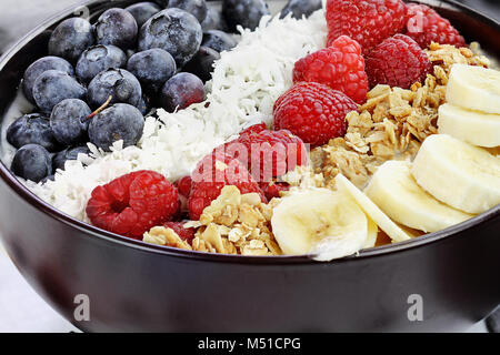 Breakfast Buddha bowl filled with chia pudding, sugar free coconut, homemade granola, fresh blueberries, raspberries and bananas. Extreme shallow dept Stock Photo