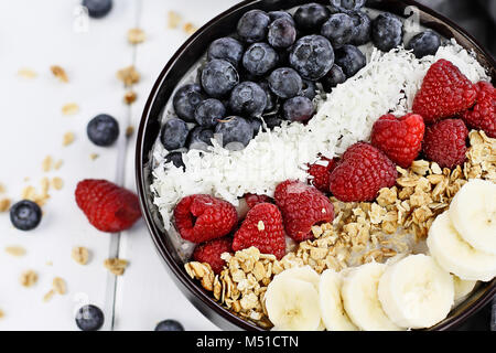 Breakfast Buddha bowl filled with chia pudding, sugar free coconut, homemade granola, fresh blueberries, raspberries and bananas. Extreme shallow dept Stock Photo