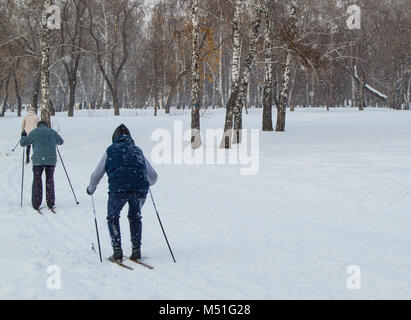 Two old people go skiing in winter Park. The view from the back Stock Photo