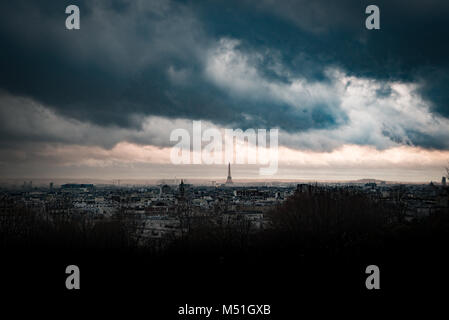 Heavy dark stormy clouds in very dramatic and threatening sunset sky over Paris and Eiffel tower, from afar Stock Photo