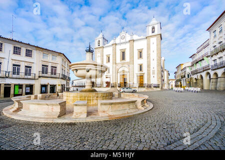 Low-angle shot of a fountain surrounded by traditional residential building and with Saint Anton's Church in the background, Giraldo Square, Evora, Al Stock Photo