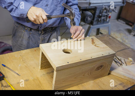 Carpenter doing assembly a birdhouse in the workshop Stock Photo