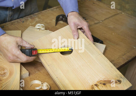 Carpenter makes a birdhouse in the workshop, uses roulette Stock Photo