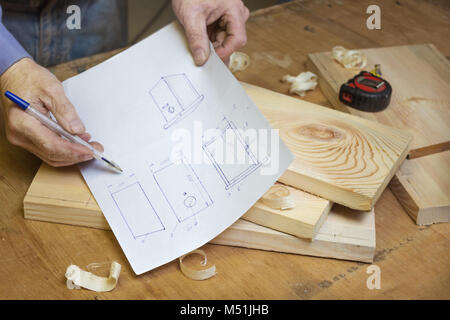 Carpenter is studying the drawing of a birdhouse in the workshop Stock Photo