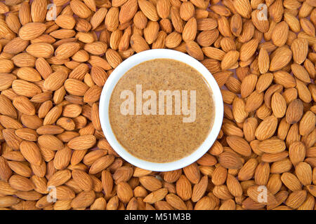 White bowl with fresh almond butter surrounded by almonod nuts. Almonds are California's third-leading agricultural product in the United States. Stock Photo