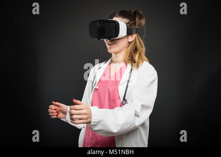 Female doctor wearing virtual reality glasses and gesturing on black background Stock Photo