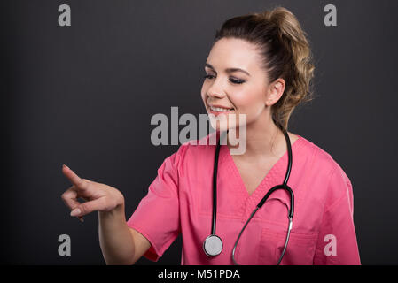Portrait of beautiful young doctor using touchscreen with index finger on black background Stock Photo