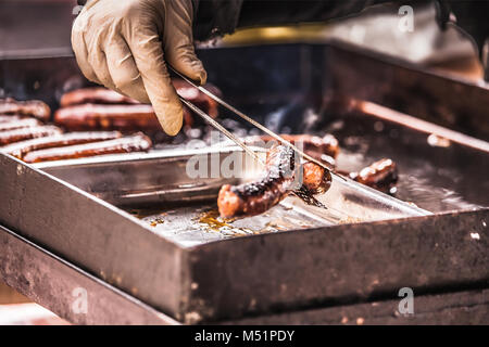 Close up hands holding homemade sausage roasted on a grill, selective focus and small depth of field Stock Photo