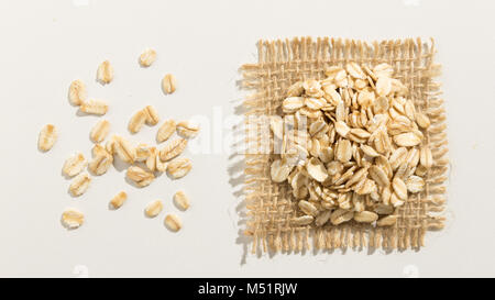 Avena Sativa is scientific name of Oat cereal grain. Also known as Aveia or Avena. Close up of grains spreaded over white table. Stock Photo