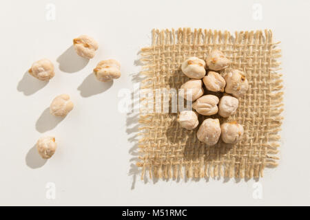 Cicer arietinum is scientific name of Chickpeas legume. Also known as Garbanzo bean, Chick Peas or Grao de Bico. Close up of grains spread over white  Stock Photo