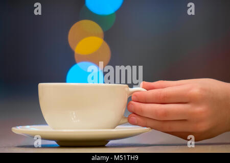 Hand holding white cup of coffee with colorful bokeh steam Stock Photo