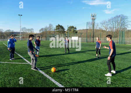 school students having a football lesson to improve their skills at playing sports on the football picth Stock Photo