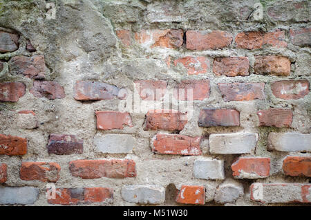 old grey concrete garage wall with red bricks and cracks abstract background Stock Photo