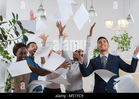 Group of excited multi racial businesspeople throwing papers in office Stock Photo