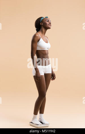 African woman standing on scale celebrating weightloss and a healthy fit body Stock Photo