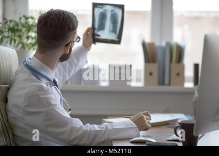 Thoughtful doctor holding chest and lungs xray in medical office Stock Photo