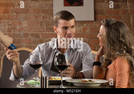 Happy couple in restaurant pay cash free by credit card electronic security money Stock Photo