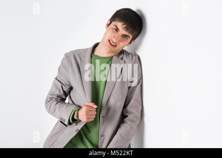 Happy smiling young man leaning against white wall with copy space an the right Stock Photo