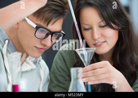 High School students. Couple of students working at chemistry class: mixing reagent liquids and using glassware Stock Photo