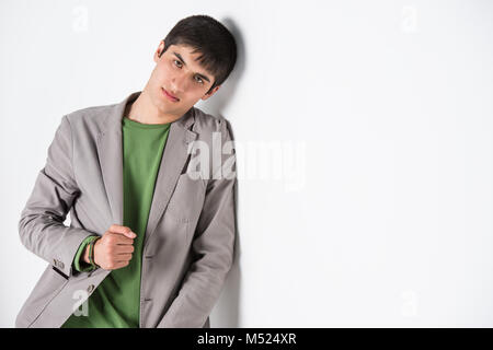 Serious young man leaning against white wall with copy space an the right Stock Photo