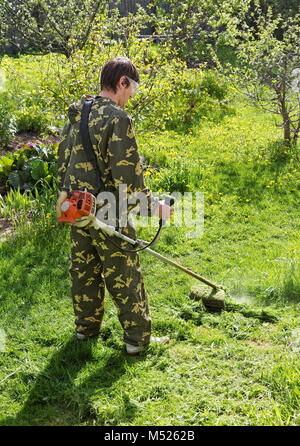 Man mows the grass in his garden summer day Stock Photo