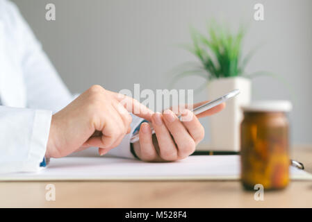Doctor using smartphone app in hospital office, close up of female person hands holding mobile phone. Modern technology in health care and medicine. Stock Photo