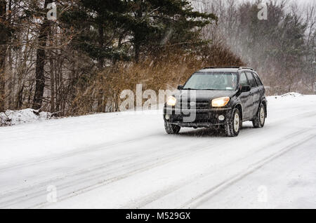 Black SUV driving on rural road in heavy snow fall. Stock Photo