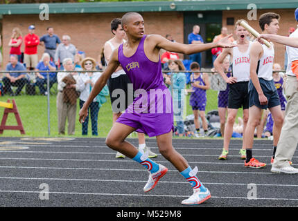 Teen boy accepts baton in relay race at outdoor track and field meet in Albany, NY on May 14, 2015. Stock Photo